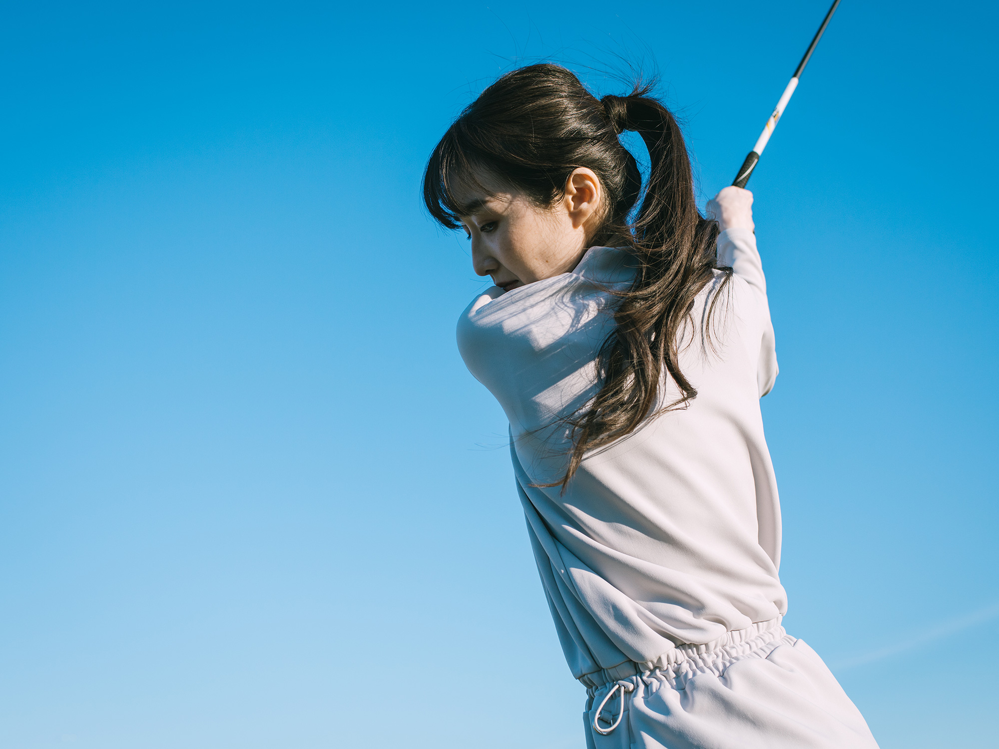 yosoro&.のウェアを着てゴルフをする女性